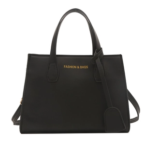 Minimalist black square tote bag in matte faux leather with dual handles and long strap