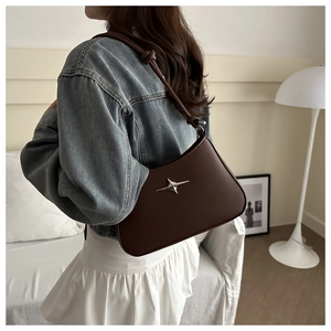 Detail of dark brown leather underarm bag featuring silver star metal buckle and knotted strap