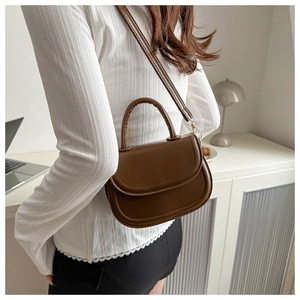 Detail of a vintage dark brown saddle bag with fine leather texture and curved flap