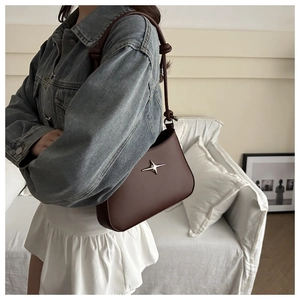 Detail of burgundy underarm bag featuring a silver star motif and knotted leather strap