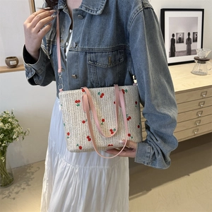 Woven straw tote bag with red cherry embroidery and pink leather straps in casual style