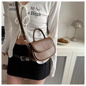Detailed view of a brown vintage saddle bag with gold hardware and adjustable strap