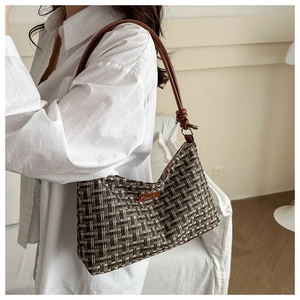 Side view of a tweed shoulder bag with leather knotted strap and fashion patch detailing