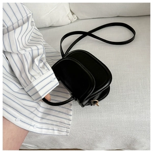 Detail of a black semi-circular saddle bag in smooth PU leather with gold metal hardware