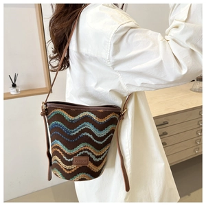 Detailed shot of wave pattern knit bucket bag with brown leather trim and fashion label