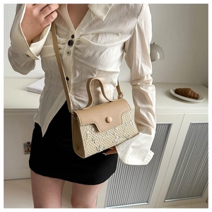 Detail van geweven crossbodytas met kaki lederen flap en witte bloemborduringen