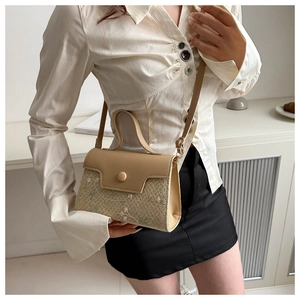 Detail van beige strooien crossbodytas met bloemenborduurwerk en elegant leren handvat