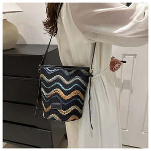 Detailed view of knitted ripple pattern and leather FASHION label on bucket bag