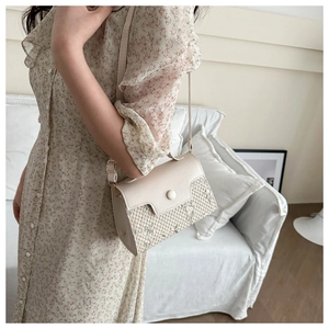 Detail van crèmekleurige crossbodytas met bloemenborduursel en stro-textuur