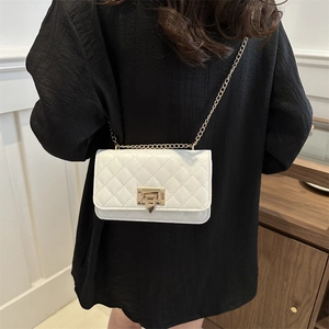 White quilted crossbody bag with gold chain strap and turn-lock on a model