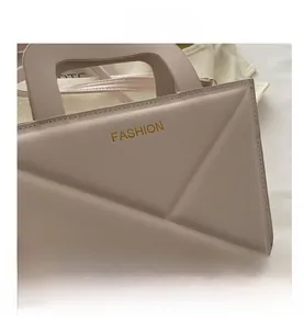 Detail of pink beige handbag featuring geometric quilted texture and gold fashion lettering