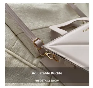 Detail of adjustable strap with gold metal buckle on quilted beige crossbody bag