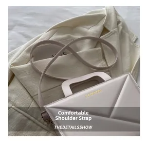 Close-up of beige geometric embossed tote bag with gold FASHION text on a suit