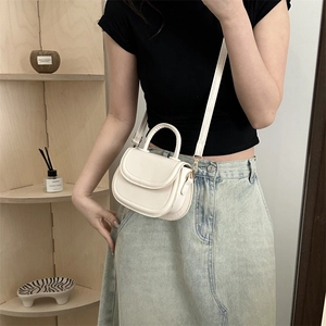 Chic white mini saddle bag with top handle and gold hardware for versatile crossbody wear