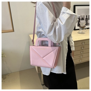 Detailansicht der rosa geometrischen Umhängetasche mit goldener Fashion-Aufschrift