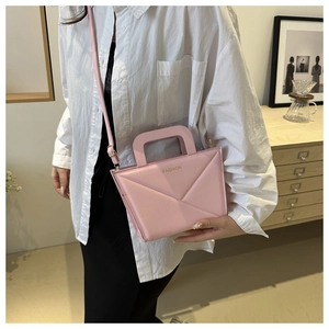 Close-up of pink leather crossbody bag with geometric stitching and gold FASHION text