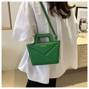 Detailansicht der grünen geometrischen Handtasche mit goldenem Schriftzug und Riemen