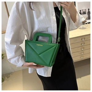 Detailed view of green geometric leather bag showing 3D folding design and fashion logo