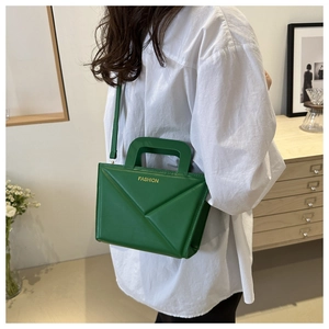 Detail der grünen geometrischen Handtasche mit modischem Schriftzug und Faltung