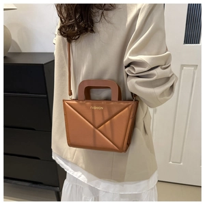 Brown geometric crossbody bag detail showing triangular folding pattern and golden text