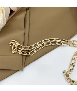 Close-up of a polished gold metal chain strap on a woven shell bag accessory
