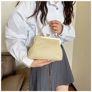 Close-up of woven straw shell bag with golden heart clasp and pearl top handle
