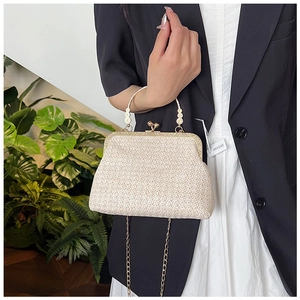 Detail of woven straw bag featuring gold clasp and daisy floral metal handle