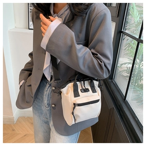 Gros plan sur un mini sac seau en toile blanc cassé avec bandoulière noire sur modèle
