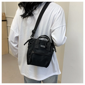 Détail d'un sac bandoulière en toile noire avec l'étiquette logo en silicone S SPORT