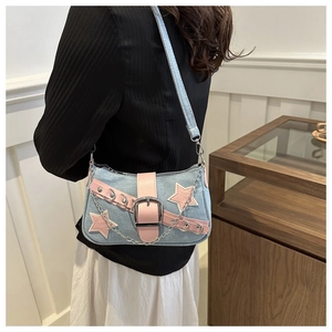 Detail of blue denim bag with pink leather trim, star patches and silver chain strap