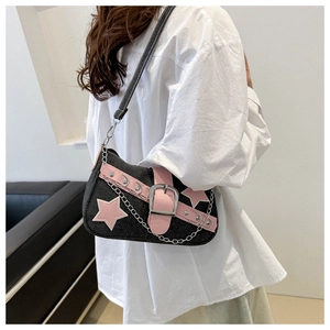 Detail of a black denim underarm bag with pink stars and metal chain straps on a model