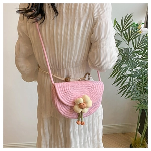 Detailed knit texture of pink handmade crochet saddle bag with floral accent on white dress