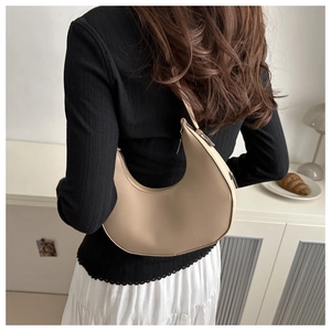 Close-up of minimalist beige crescent shoulder bag with smooth faux leather texture