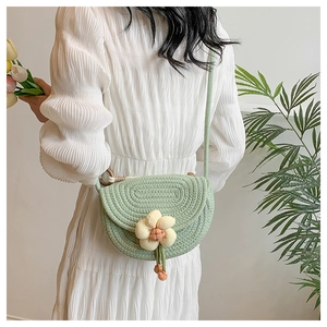 Detail of hand-woven green cotton saddle bag with 3D floral accent and woven strap
