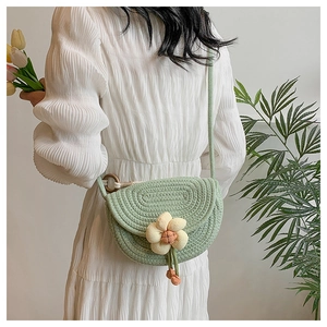 Detail of mint green woven crossbody bag with white flower charm and wooden rings