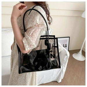 Close-up of a large black transparent PVC tote bag with internal pouch and FASHION text