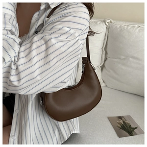 Detailed close-up of dark brown crescent underarm bag in smooth PU leather material