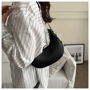 Minimalist black crescent hobo bag in smooth leather worn with a striped shirt