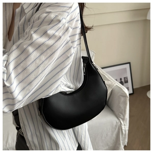Minimalist black crescent hobo bag made of smooth matte leather shown on a model