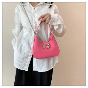 Gros plan du sac en cuir rose avec boucle nœud en métal argenté et bandoulière chaîne