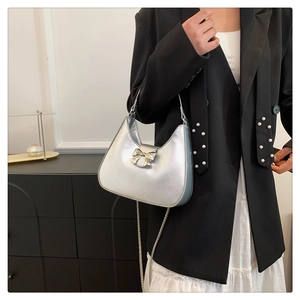 Détail du sac hobo argenté avec nœud chromé et bandoulière élégante en chaîne