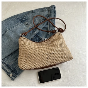 Detailed view of woven straw texture and brown leather strap on hobo shoulder bag