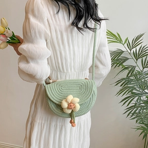 Light green woven saddle crossbody bag with floral pendant for summer fashion