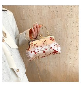 Detail of pink embroidered shell bag with plum blossom pattern and golden ring handle