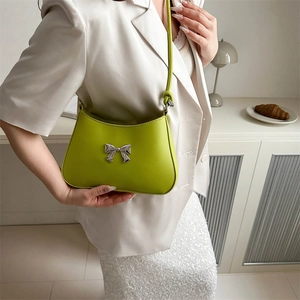 Chic avocado green shoulder bag with silver bow accent and minimalist rounded silhouette