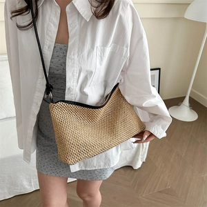 Fashionable woven straw shoulder bag with black leather straps for beach vacations