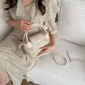 Minimalist beige woven handbag with floral embroidery and adjustable leather strap