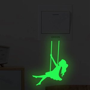 Luminous wall sticker featuring a girl on a swing glowing green in a dark room setting
