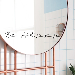 Minimalist round rose gold mirror with Be Happy text quote on white tile wall