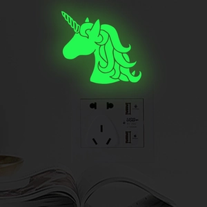Luminous unicorn wall sticker glowing in dark near a wall power socket and a book